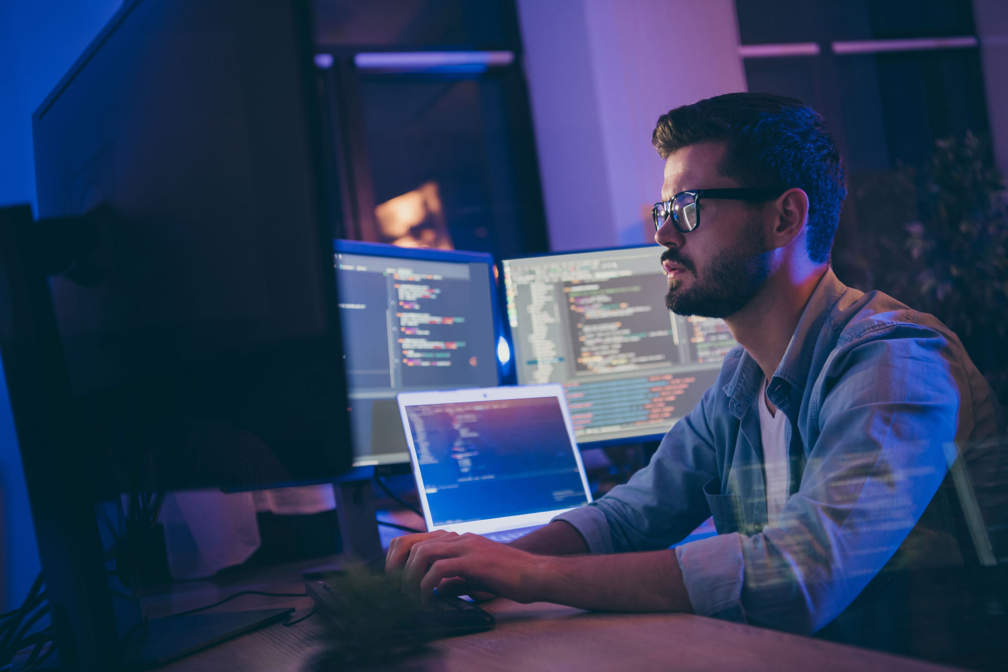 A man with several computers reading information about NetSuite help