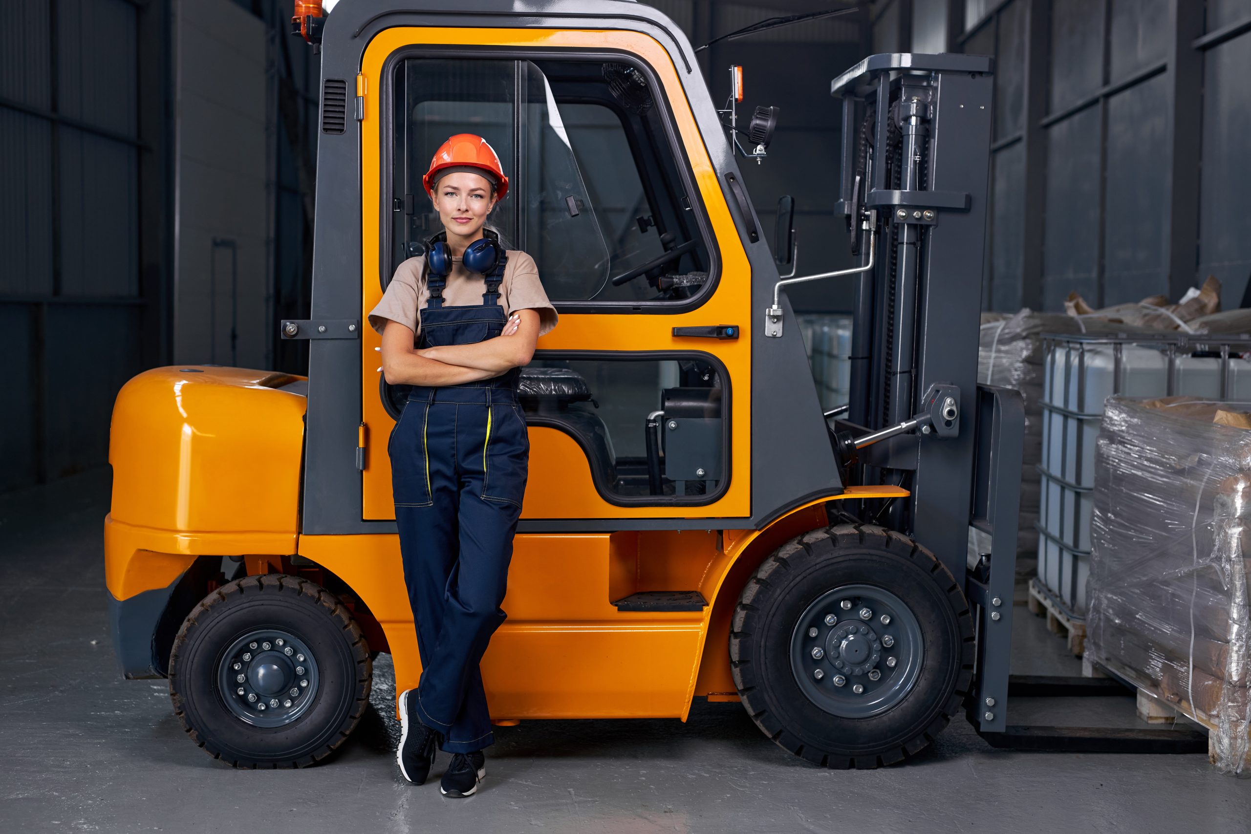 A woman standing in front of a forklift