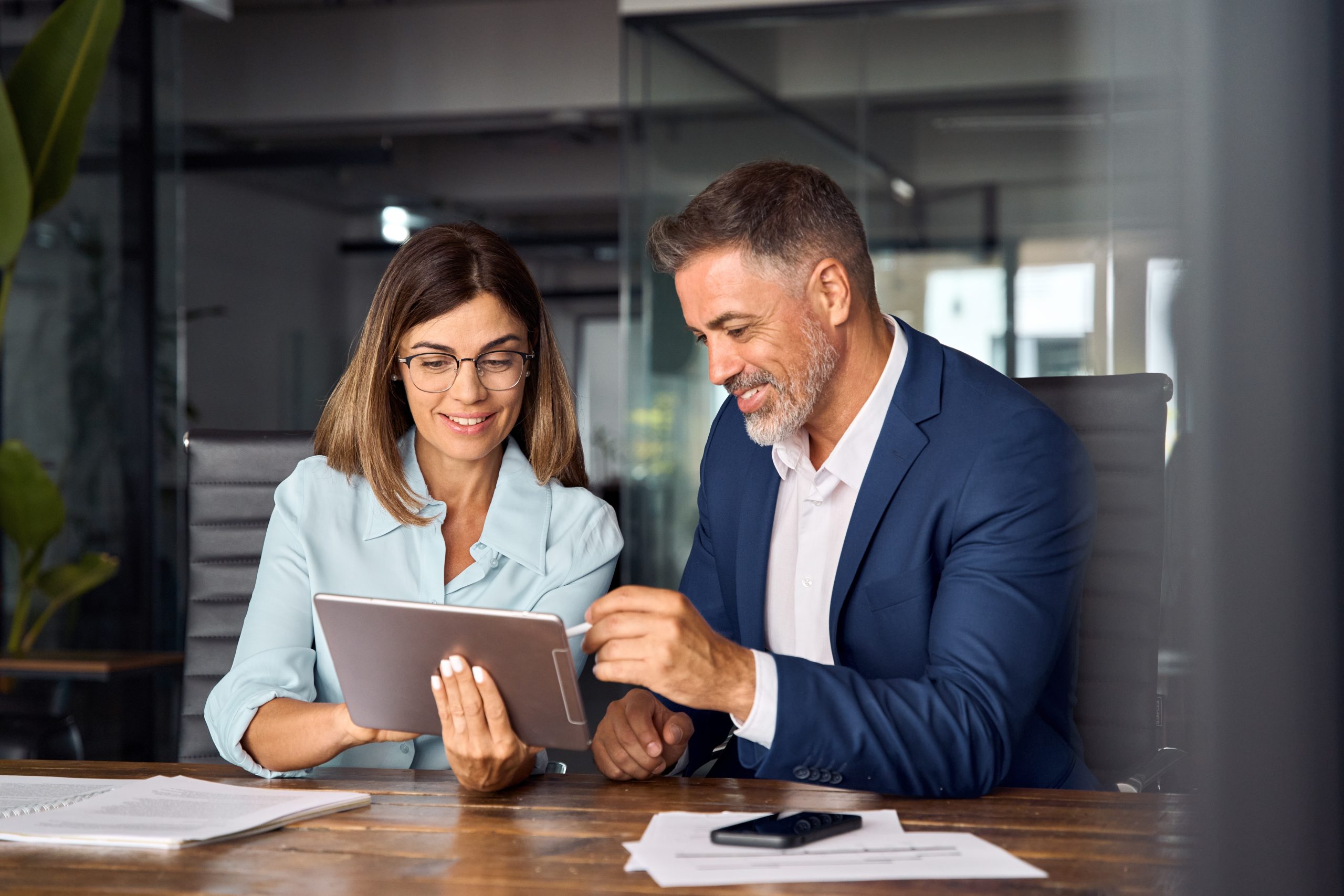 A business man and business woman looking at a tablet with information about NetSuite Support Services