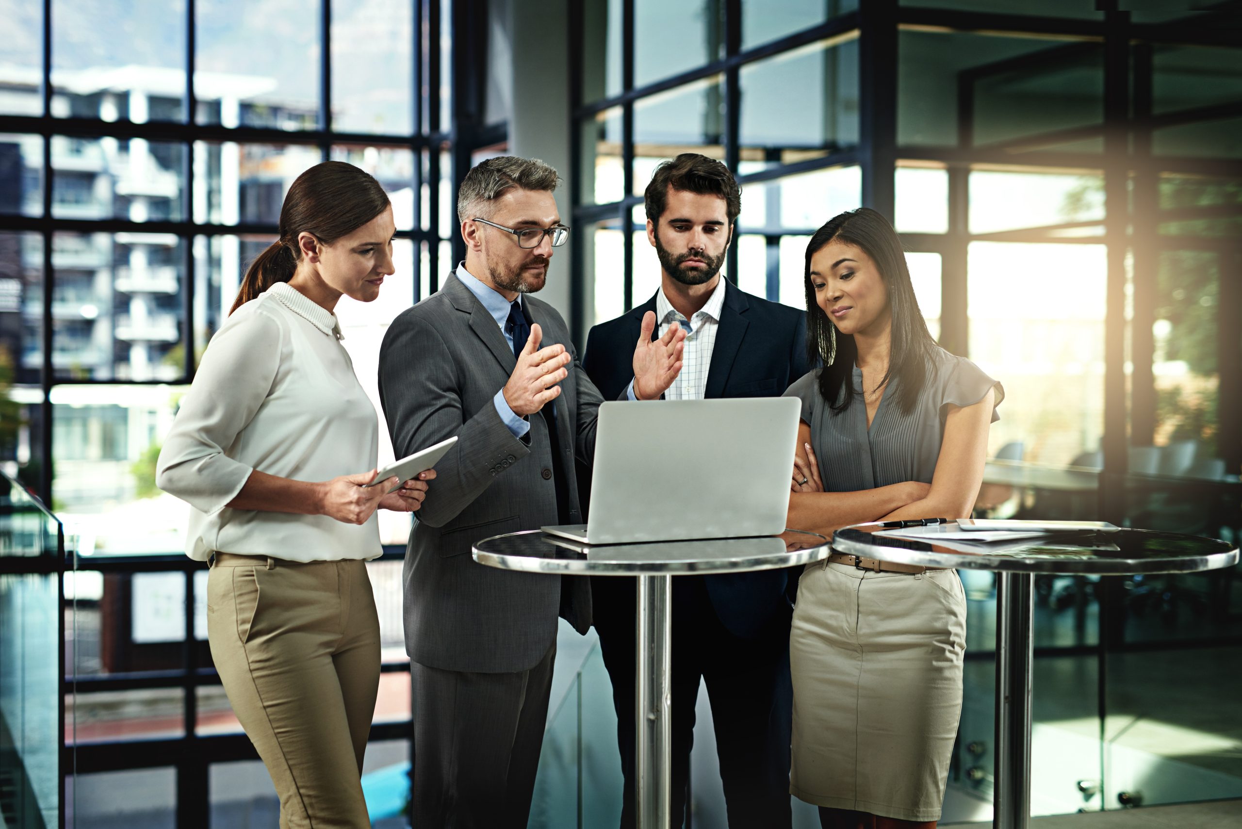 Business people in an office discussing NetSuite Customer Support on a laptop.